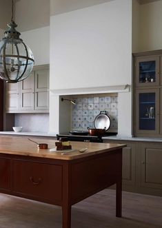 a kitchen with an island in the middle and a light fixture hanging from the ceiling