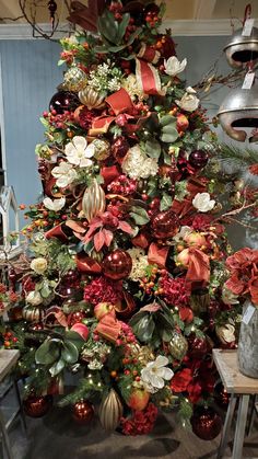 a christmas tree is decorated with red and green flowers, berries, and other holiday decorations