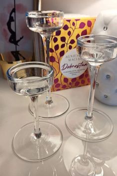 two empty wine glasses sitting on top of a table next to a box and candle holder