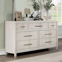 a dresser with two vases on top of it next to a mirror and lamp