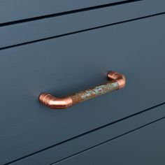 an old rusted metal handle on a blue painted dresser drawer with wood grains