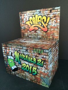 a cardboard box with graffiti on it sitting in front of a brick wall and door