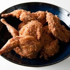 fried chicken on a black plate sitting on a white table