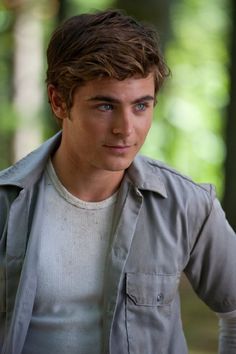 a young man is posing for a photo in the woods with his hands on his hips