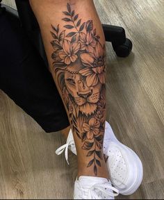 a woman's leg with a lion and flowers tattoo on her left calf area