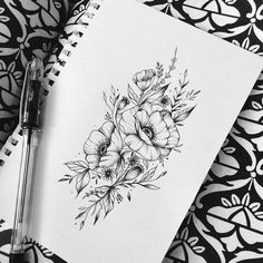 a notebook with some flowers on it next to a pen and ink drawing pencils