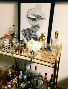 a bar cart filled with liquor bottles and glasses on top of a wooden floor next to a wall