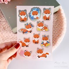 a person holding up a sticker sheet with foxes on it