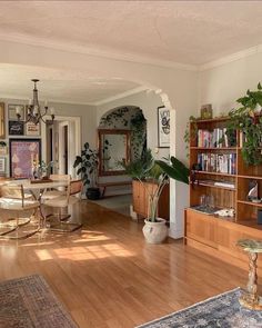 a living room filled with lots of furniture and plants on top of wooden flooring