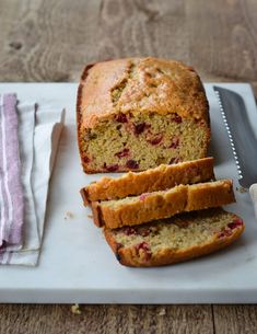 sliced loaf of fruit bread sitting on top of a cutting board next to a knife