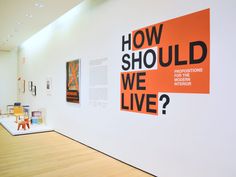 an orange and black sign hanging on the wall next to a white wall with pictures