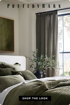 a bed sitting next to a window in a room with green sheets and blankets on it