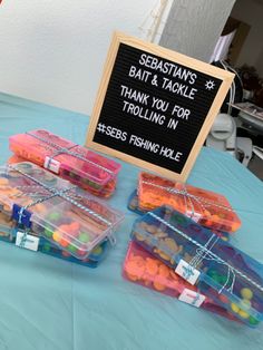 there are many plastic containers on the table with candy in them and a sign that says sebastian's bat & tackle thank you for trolling in