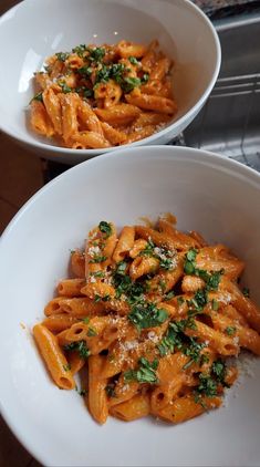 two white bowls filled with pasta and parmesan sprinkled on top of each other