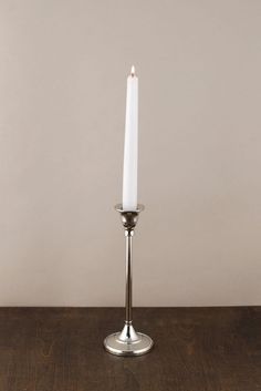 a single white candle sitting on top of a wooden table