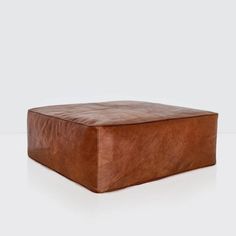 a brown leather ottoman sitting on top of a white floor