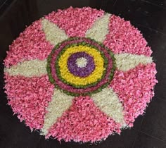 a circular flower arrangement on the floor in pink, yellow and green colors with white petals