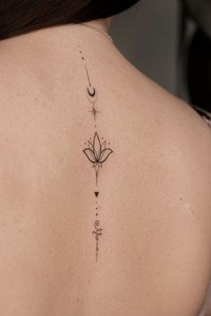 the back of a woman's neck with a flower and arrow tattoo on it