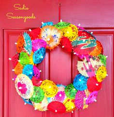 a colorful wreath with umbrellas hanging on a red door