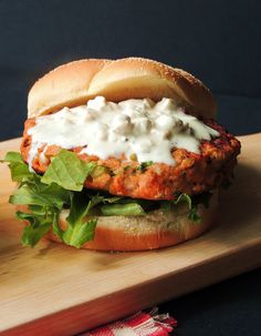 a sandwich with meat, lettuce and sour cream on a wooden cutting board