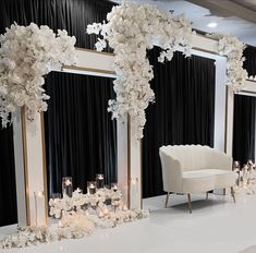 an elegant wedding setup with white flowers, candles and black drapes on the wall