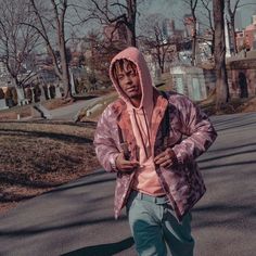 a young man wearing a pink hoodie and blue pants is walking down the street