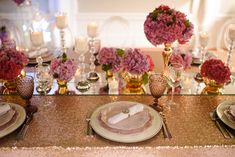 the table is set with pink flowers and silverware