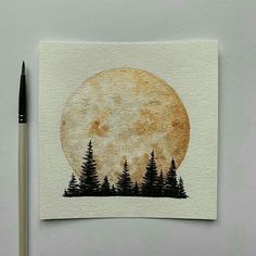 a painting of trees and the moon with a pen in front of it on top of a piece of paper