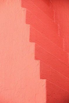 a red wall with some steps painted pink