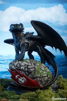 a statue of a black dragon sitting on top of rocks