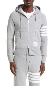 Engineered stripes at the left sleeve play up the sporty look of a cotton French terry hoodie featuring ribbed side panels for enhanced comfort and mobility. Tricolor aglets and a name tag at the hem are customary Thom Browne touches. 26" length (size 2) Drawstring hood Two-way front-zip closure Split kangaroo pocket Ribbed cuffs and hem 100% cotton Dry clean or hand wash, dry flat Made in Japan Sporty Double-lined Hood Sweats For Spring, Sporty Spring Sweats With Double-lined Hood, Sporty Hoodie With Ribbed Waistband For Spring, Sporty Spring Hoodie With Ribbed Waistband, Casual Winter Sweatshirt With Signature Stripes, Athleisure Sweatshirt With Three Stripes For Fall, Athleisure Three Stripes Sweatshirt For Fall, Sporty Cotton Hoodie With Three Stripes, Sporty Cotton Hoodie With Ribbed Waistband