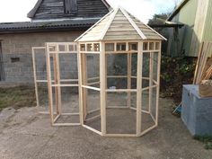 a small wooden bird cage sitting next to a building