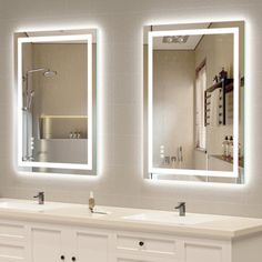 a bathroom with two sinks, mirrors and lights on the wall above them is shown