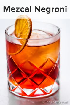 a close up of a drink in a glass with an orange slice on the rim