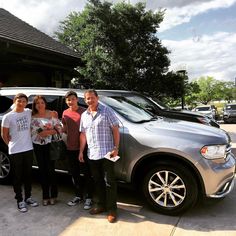 four people standing in front of a car