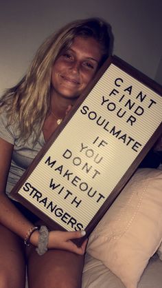 a woman holding a sign that says can't find your soulmate if you don't make out with strangers