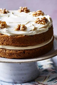 a cake with white frosting and walnuts on top is sitting on a plate