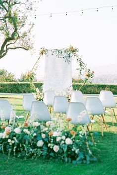 an outdoor ceremony setup with white chairs and flowers