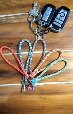 two keys are attached to a multi - colored lanyard on a wooden surface with other keychains