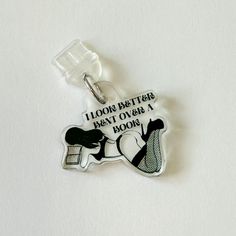 a keychain with an image of a woman holding a bottle and the words, i look better beat over a book