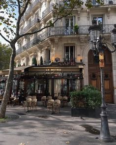 an empty street with tables and chairs in front of a building that has balconies on it