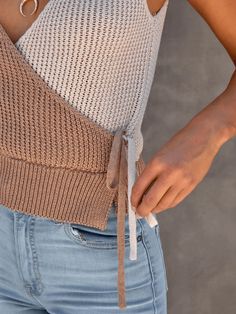 a close up of a person wearing jeans and a sweater with a tie around the waist