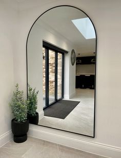 an arched mirror in the corner of a room with a potted plant next to it