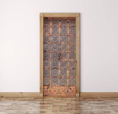 an old wooden door in a white room with wood flooring and tile on the wall