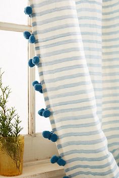 a blue and white striped curtain with pom - poms