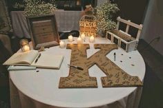 a table topped with candles and pictures next to a wooden letter shaped like the letter k