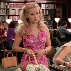 a woman in a pink dress holding a basket and sitting at a table with other people