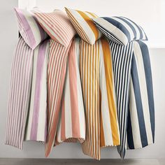 four different colored striped pillows stacked on top of each other