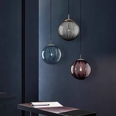 three circular glass pendants hang from the ceiling above a table in a dark room