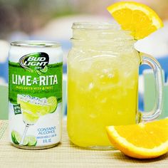 a drink in a mason jar next to a can of limeade and an orange slice